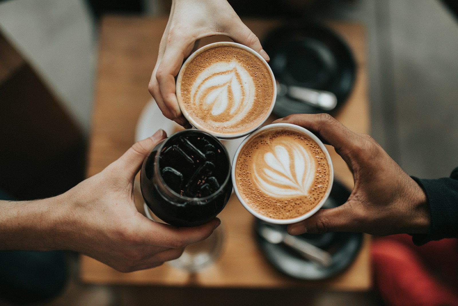 Three friends raising their cups over a café table