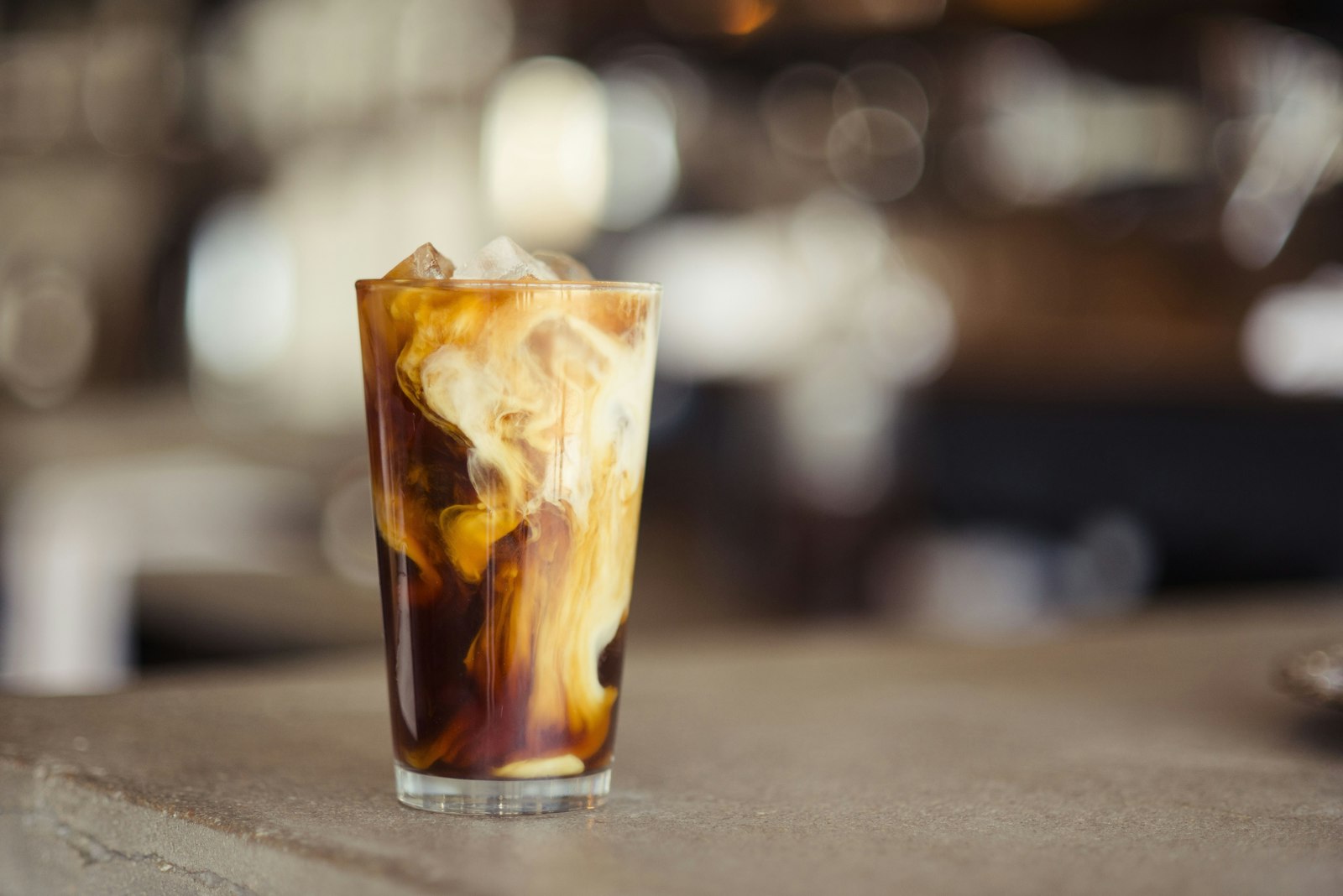 A glass of iced coffee with cream swirling through it