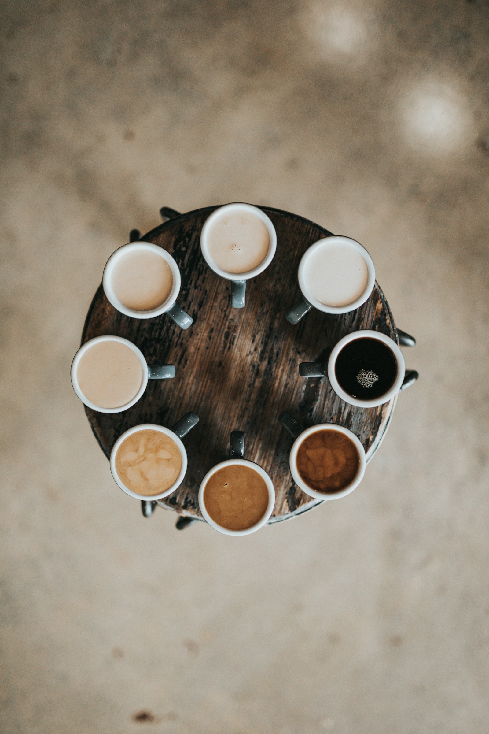 Eight cups of coffee arranged in a circle, from black to milky